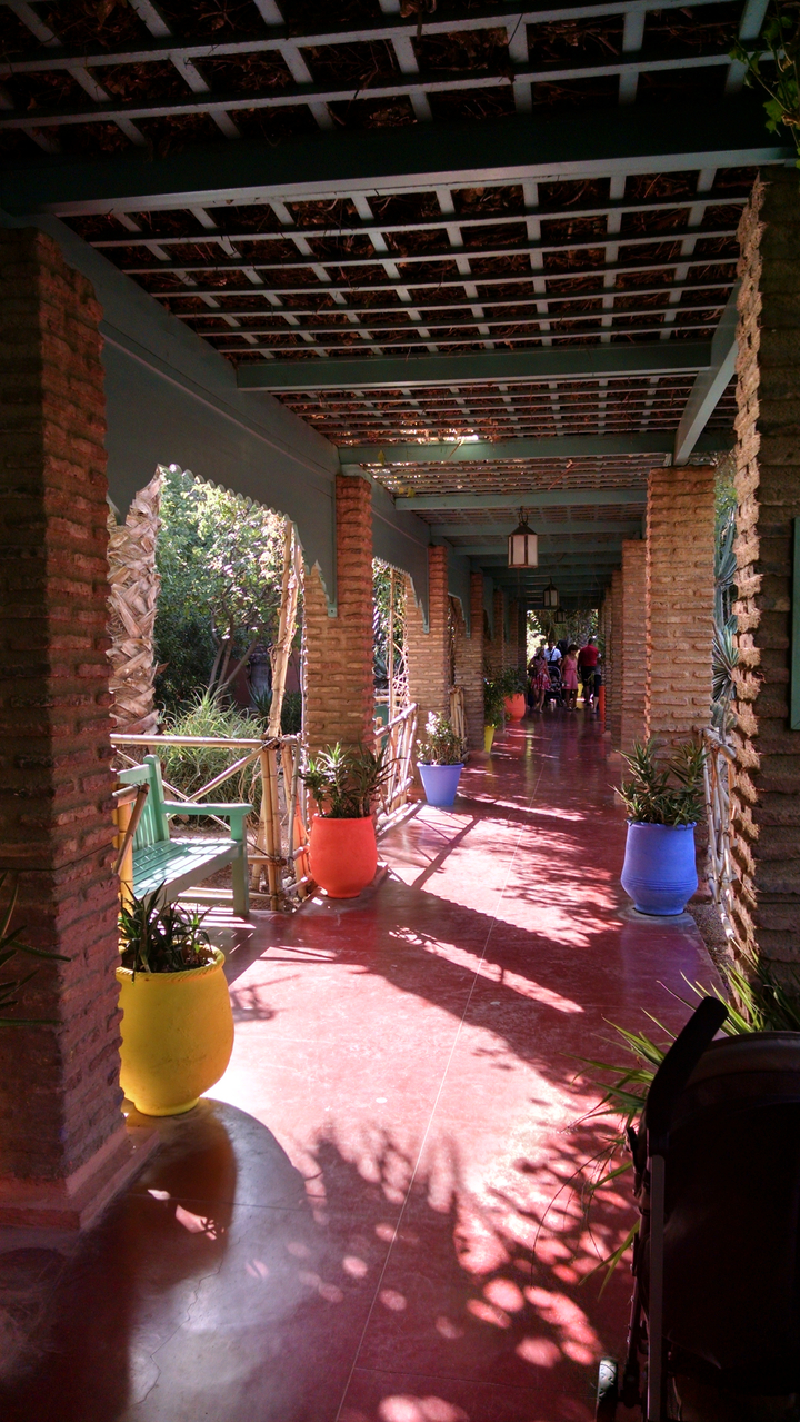 Allée en briques bordée de plantes en pot et de personnes.