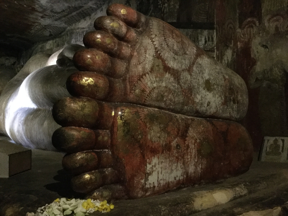 Large statue of reclining feet in an interior setting.