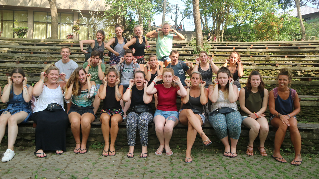 Group of people sitting on outdoor steps making faces.