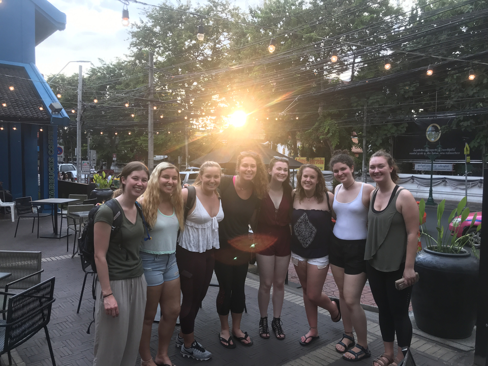 Group of friends standing together in an outdoor area during sunset.