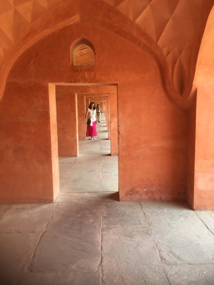 Femme debout dans un couloir à arcades.