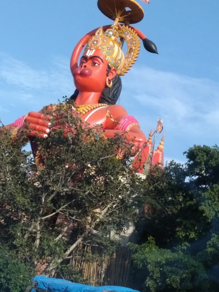 Statue colorée partiellement cachée par des arbres.