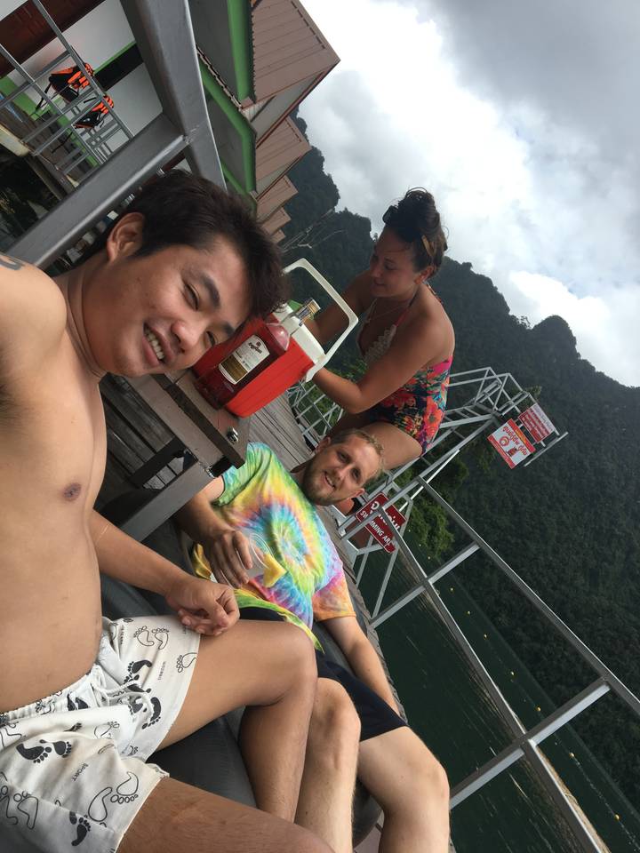 Des gens se détendant sur un ponton au bord de l'eau avec des falaises pittoresques.