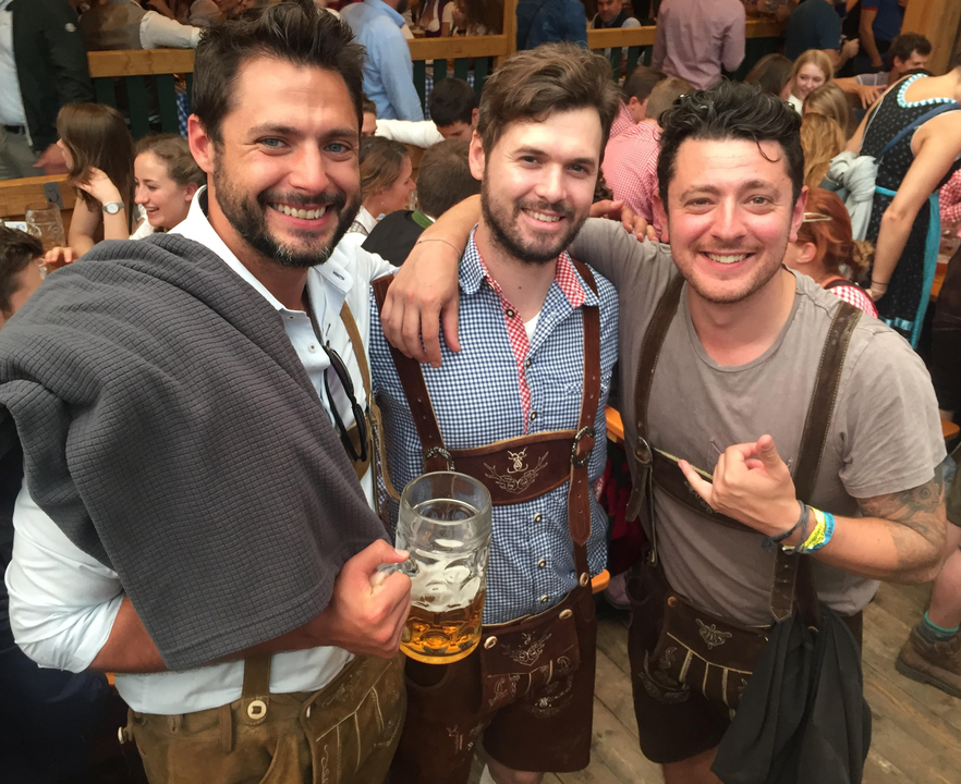 Trois hommes portant des vêtements traditionnels et tenant des chopes de bière.