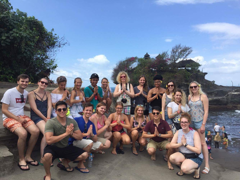 A large group posing in front of a temple structure.