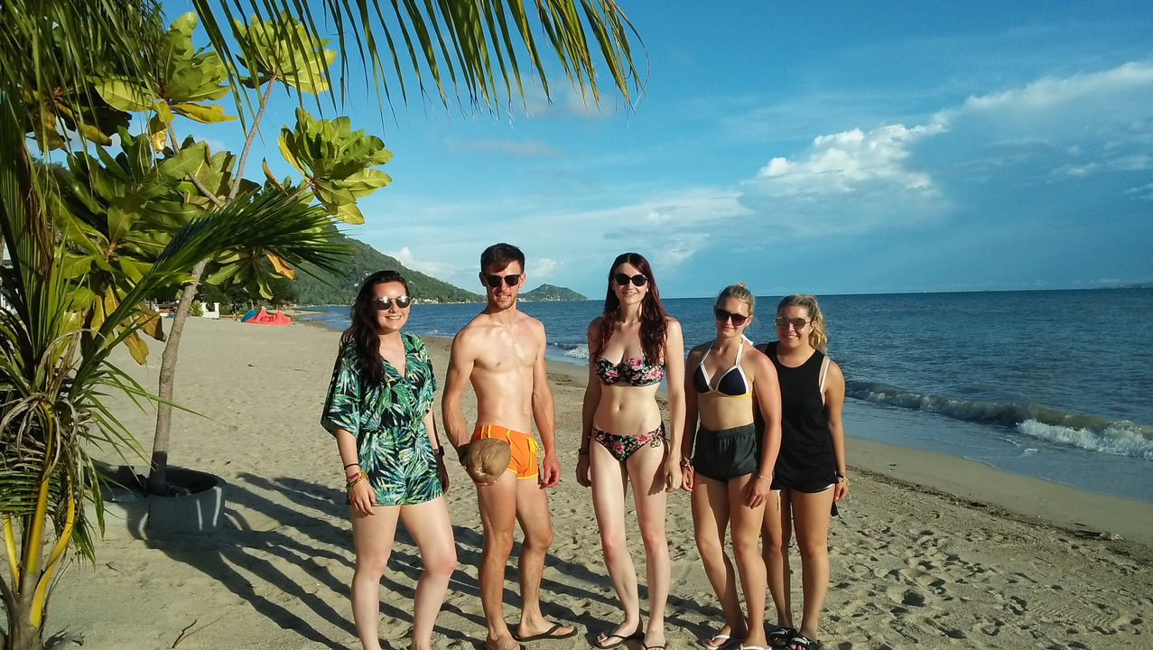 Group of people on a beach with palm trees.