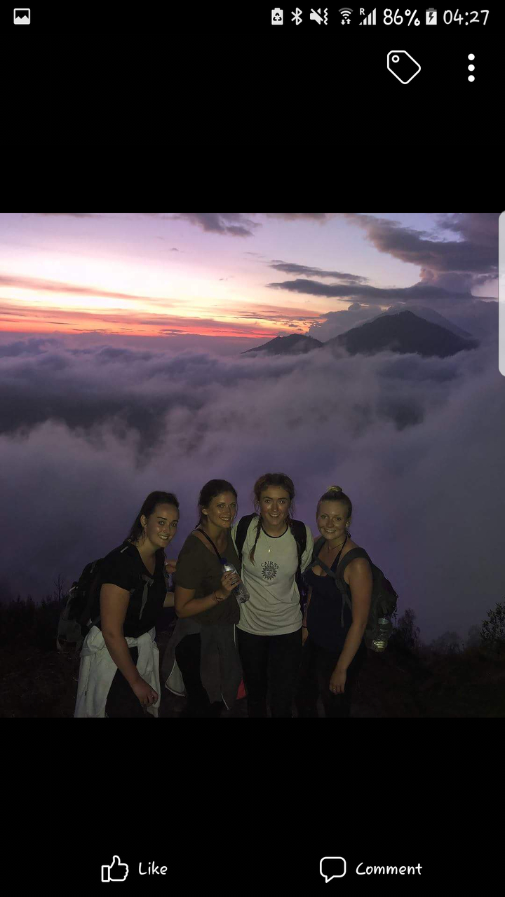 Groupe de randonneurs posant devant une vue de montagne au lever du soleil.