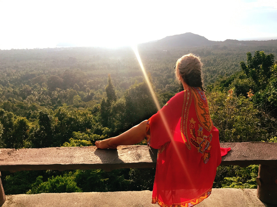 Person sitting on terrace overlooking a lush valley.