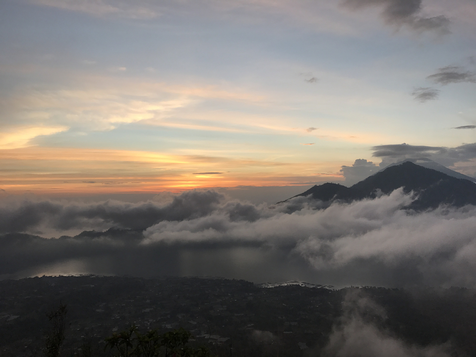 Dramatic sunset over clouds and distant mountains.