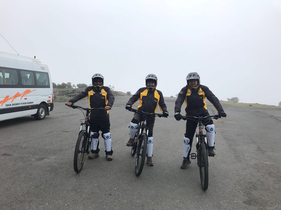 Trois cyclistes en tenue de protection posant avec leur vélo.