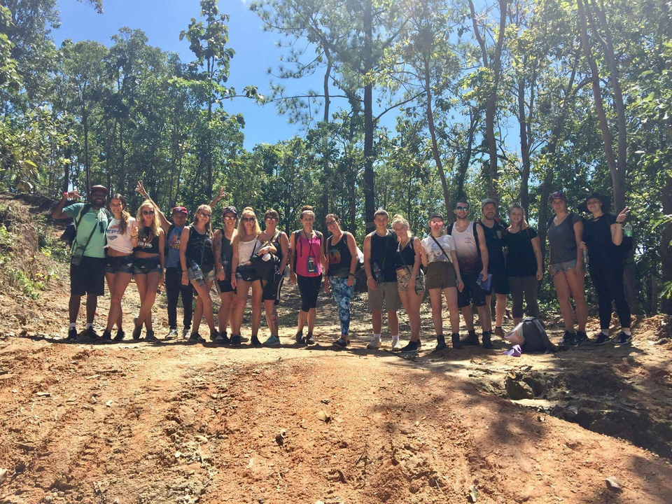 A group of people standing on a dirt path in a forest.