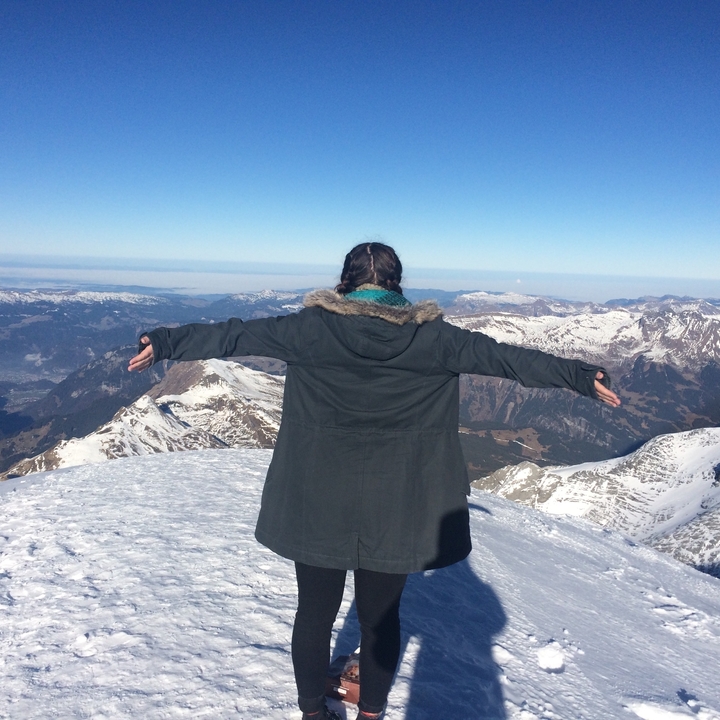 Person standing with arms outstretched on a snowy mountain.