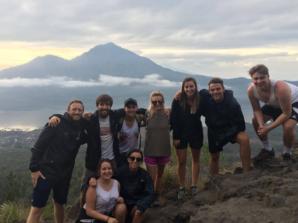 Group smiling at the camera with mountain backdrop.