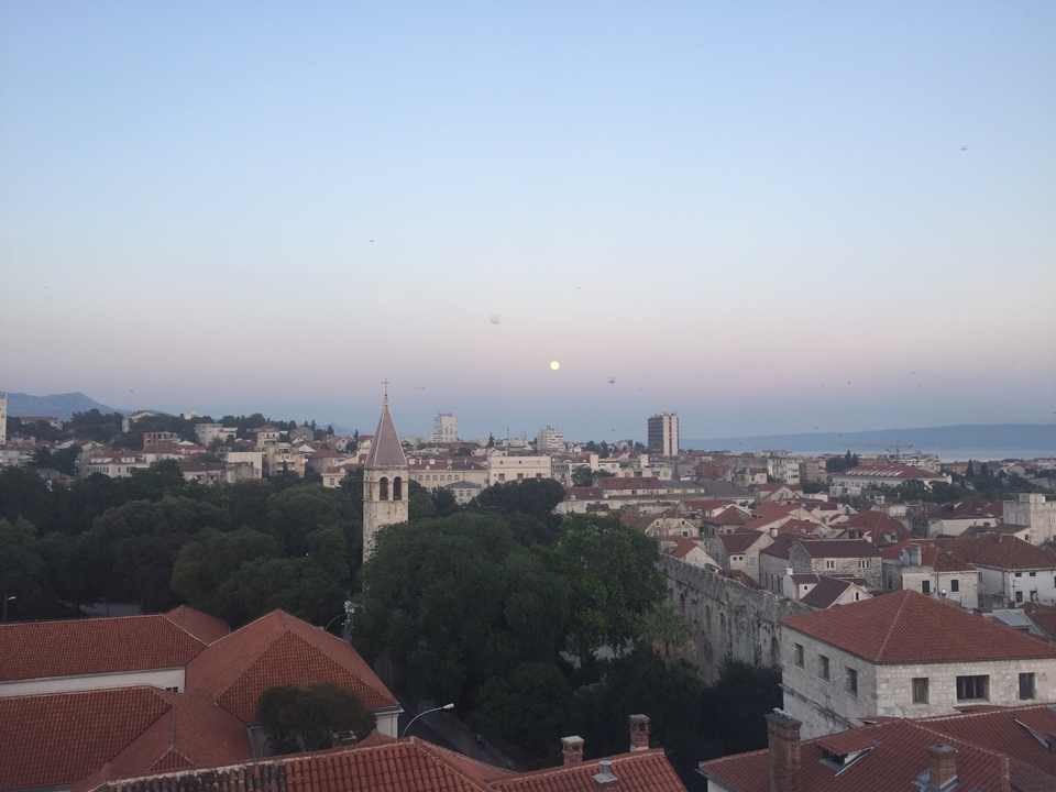 Aerial view of a coastal city with the moon in the sky.