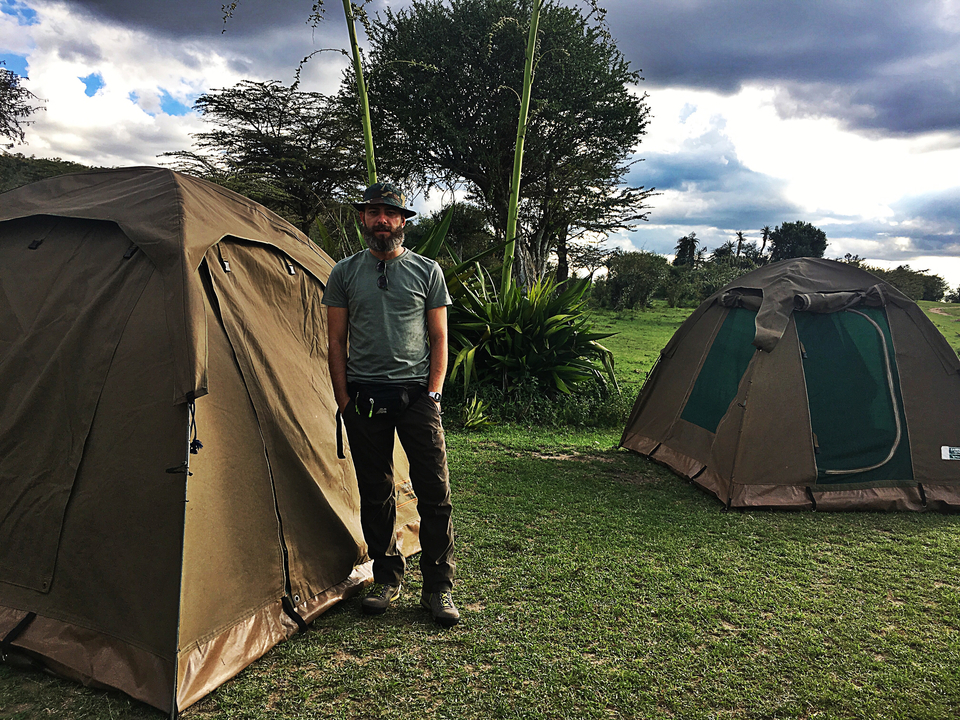 Homme debout entre deux tentes de camping.