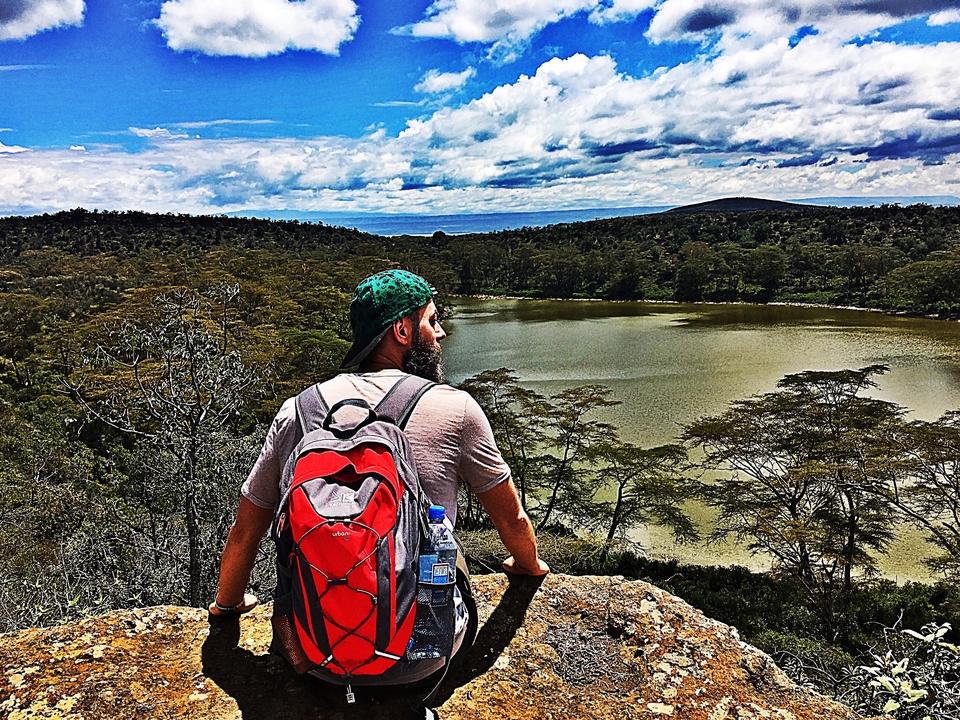 Homme avec un sac à dos surplombant un lac.