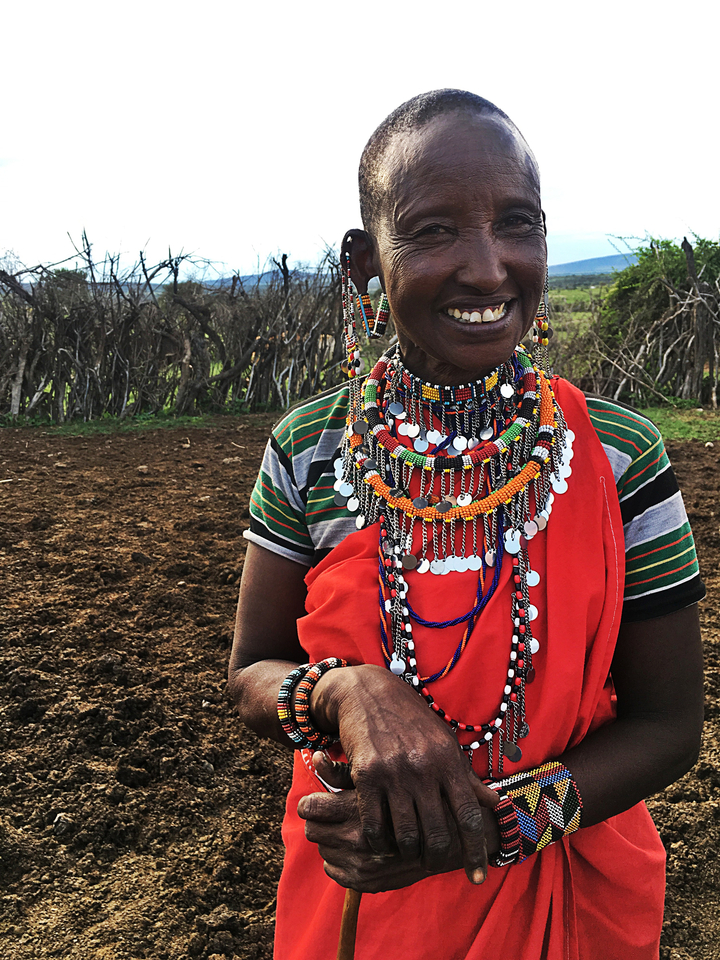 Personne souriante portant des bijoux Maasai colorés.