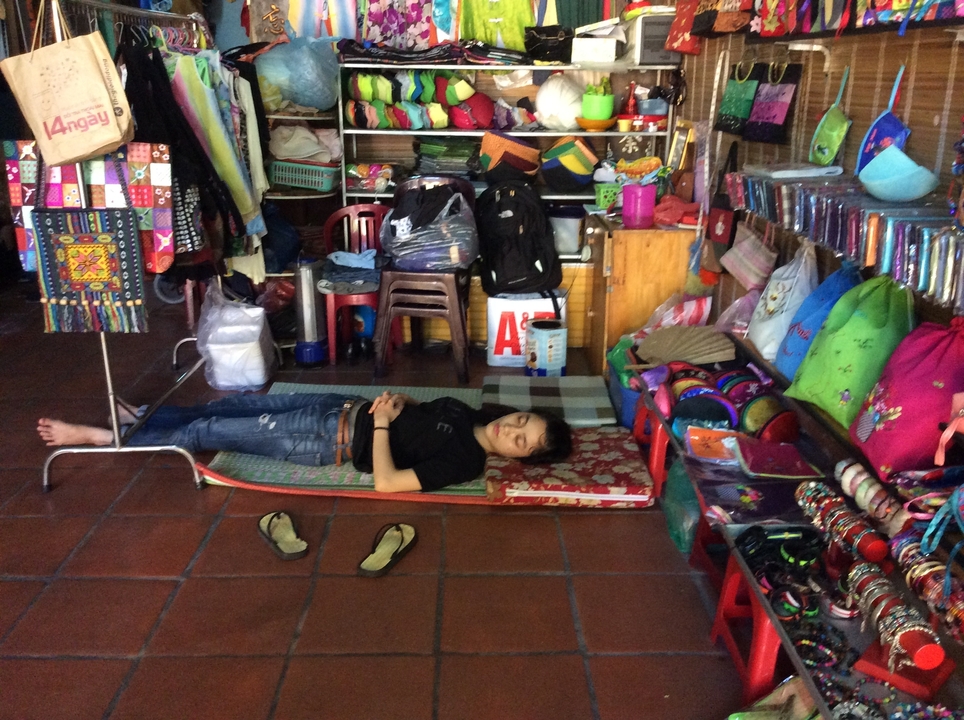 Personne allongée dans un magasin entourée de divers articles à vendre.