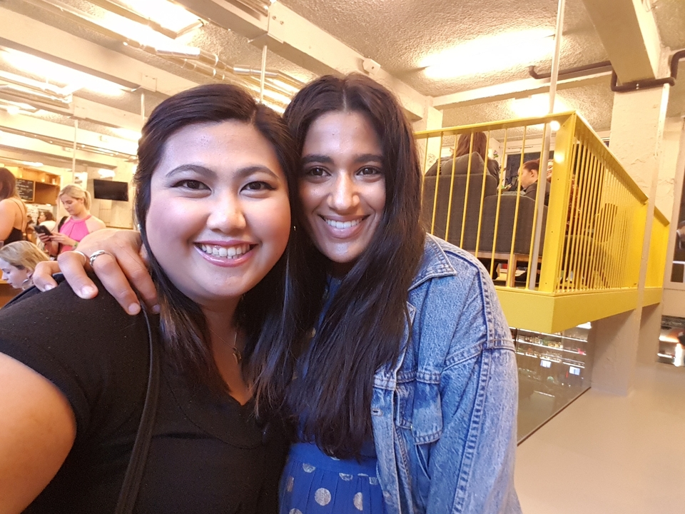 Deux femmes souriant à l'intérieur.