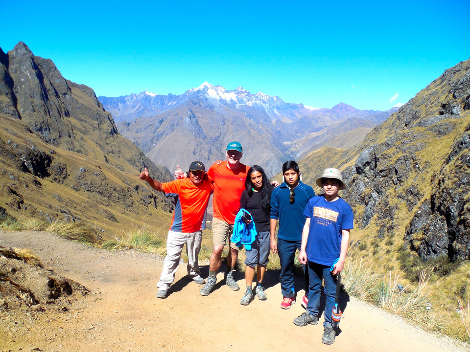 Groupe de randonneurs posant sur un sentier de montagne avec un arrière-plan pittoresque.