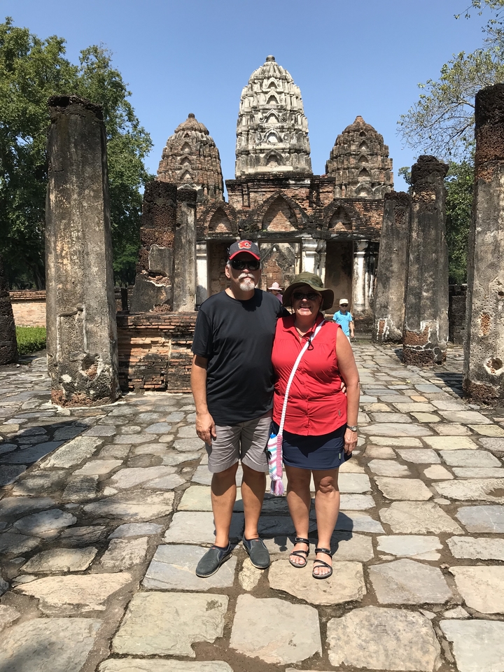 Couple posant devant des ruines anciennes.