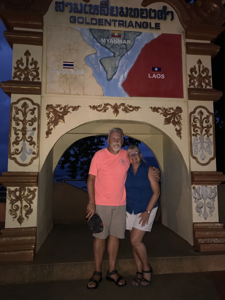 Couple posant sous une arche ornée la nuit.