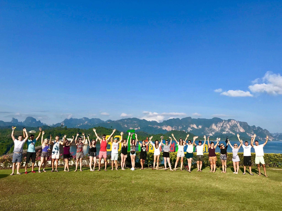 Group holding hands celebrating with mountainous backdrop.