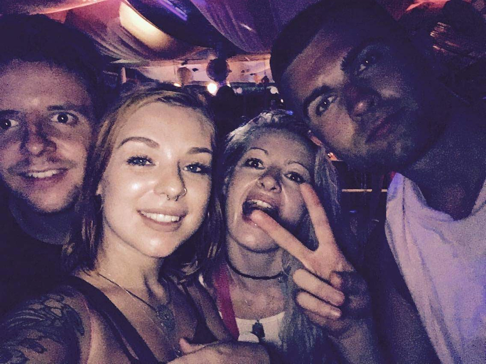 Group of people taking a selfie in a dimly lit environment.