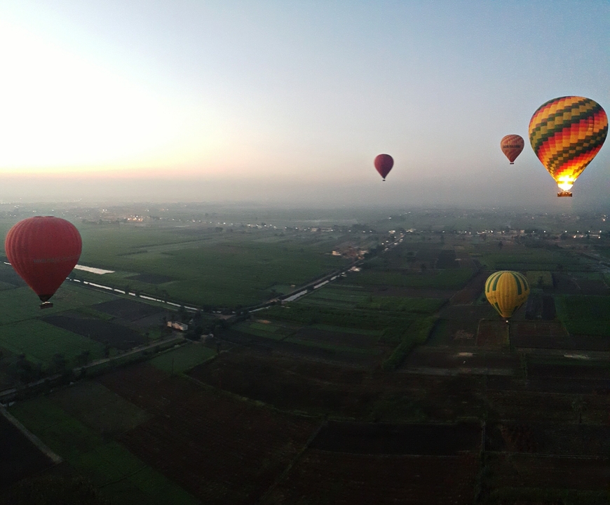 Montgolfières flottant au-dessus des terres agricoles au lever du soleil.