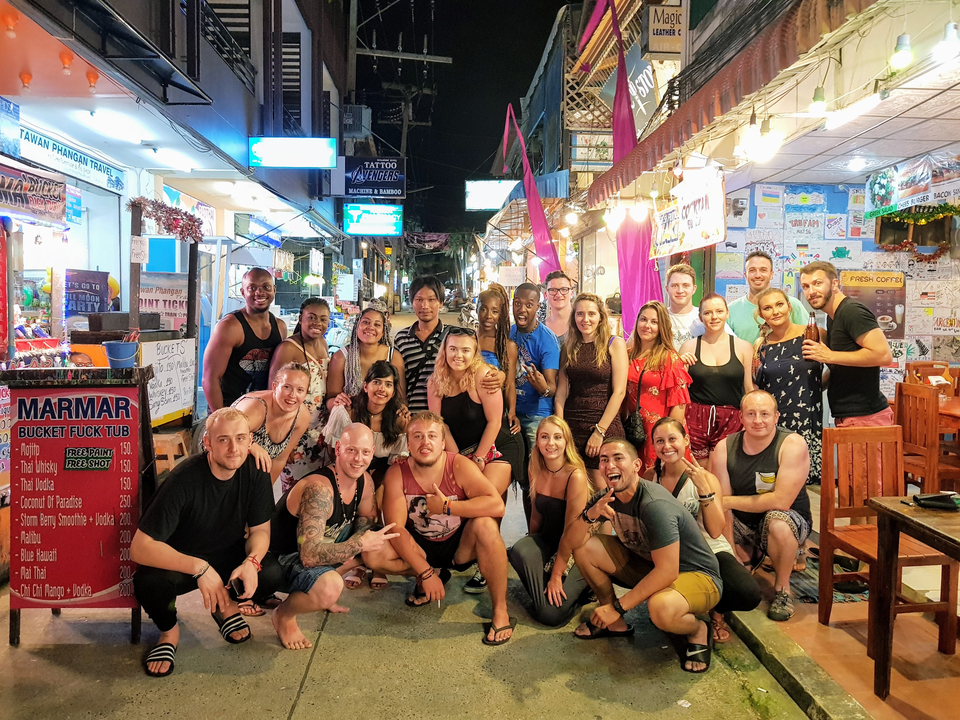 Large group of people posing on a busy street at night.