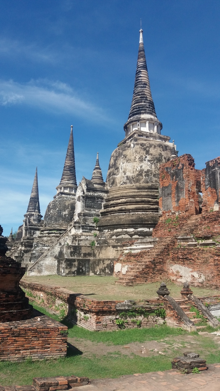 Ruines d'anciens temples avec de grands stupas sous un ciel bleu éclatant.