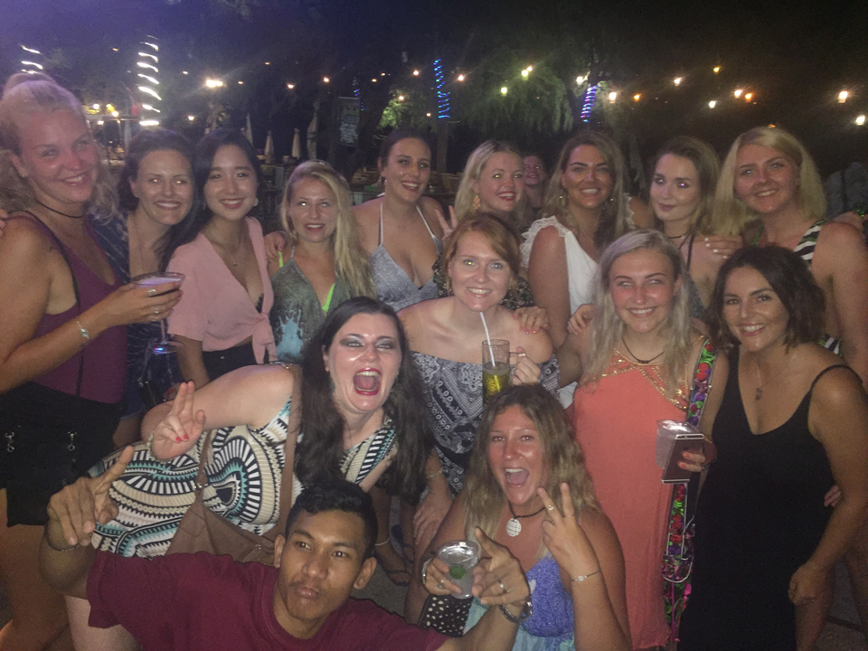 Groupe d'amis posant la nuit avec des boissons.