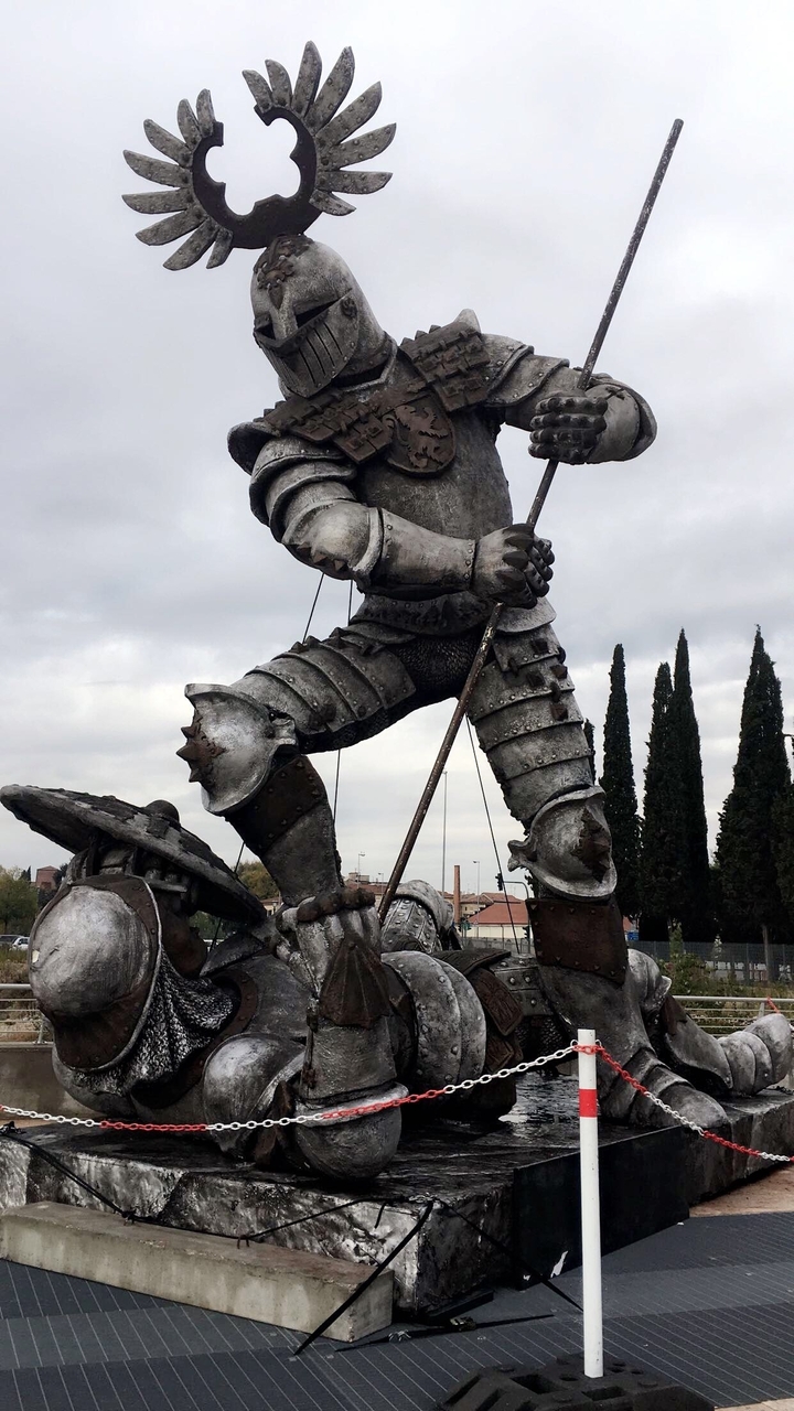 Sculpture d'un personnage médiéval en armure sur une place publique.