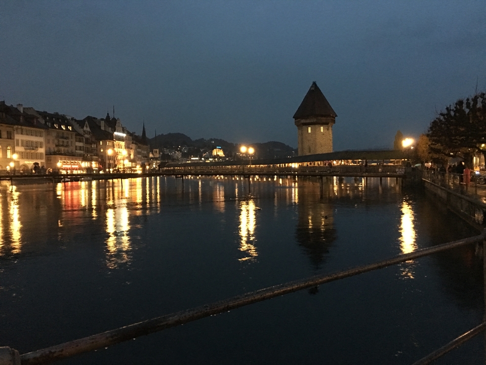 Vue nocturne d'une rivière avec un pont historique et des bâtiments illuminés.