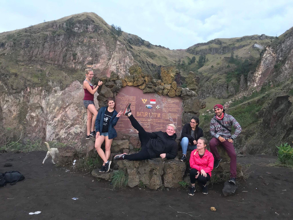 People posing near a mountain with a height sign and rocky background.