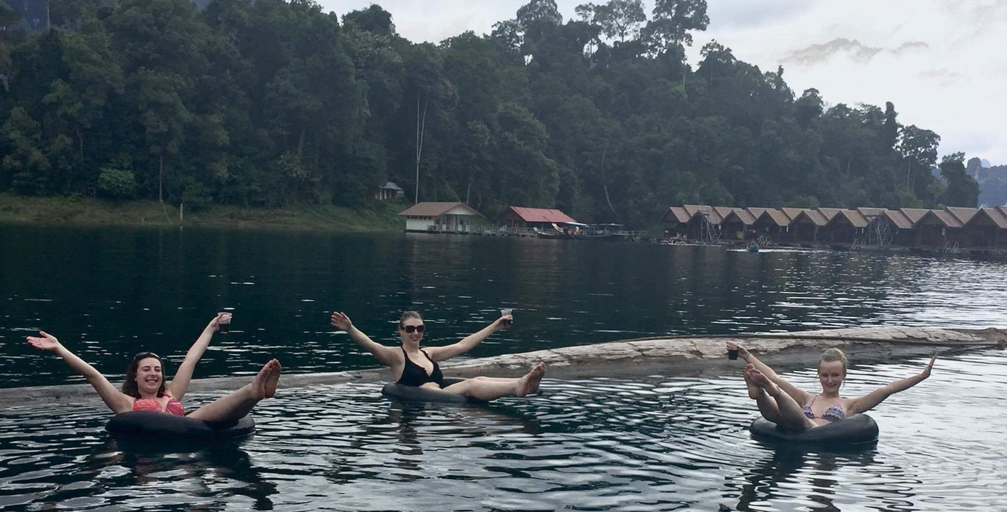 Three women floating on inner tubes on a lake.