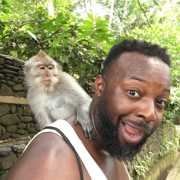 Man posing with a monkey on his shoulder.