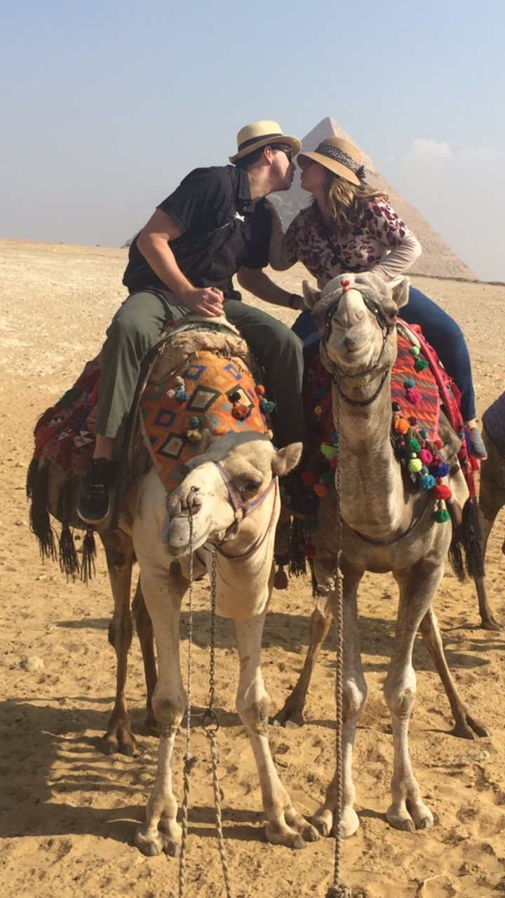 Deux chameaux aux selles colorées dans un décor désertique.