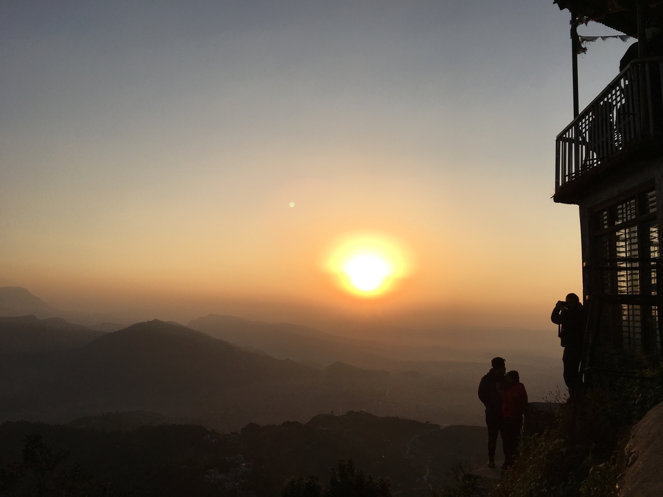 Silhouette de personnes sur un balcon lors d'un coucher de soleil coloré.