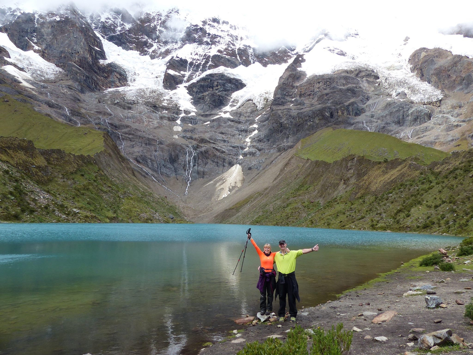Deux personnes posant devant un lac glaciaire turquoise et des montagnes.