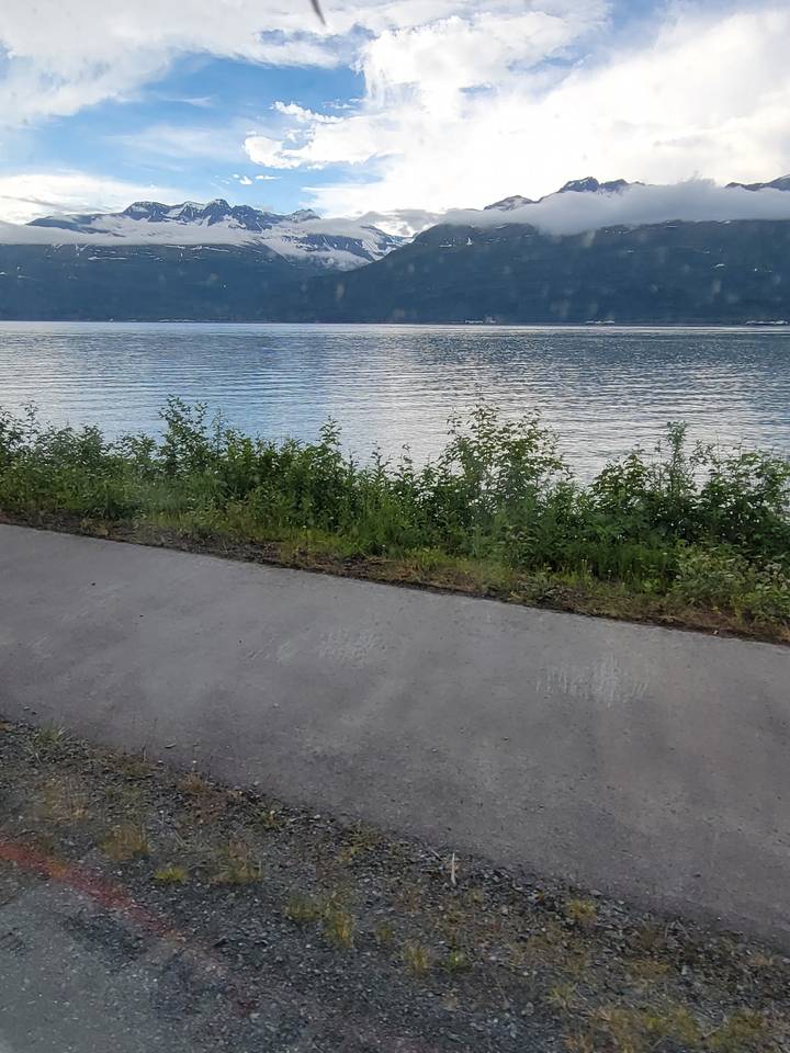 Lac pittoresque avec une route et des montagnes en arrière-plan.