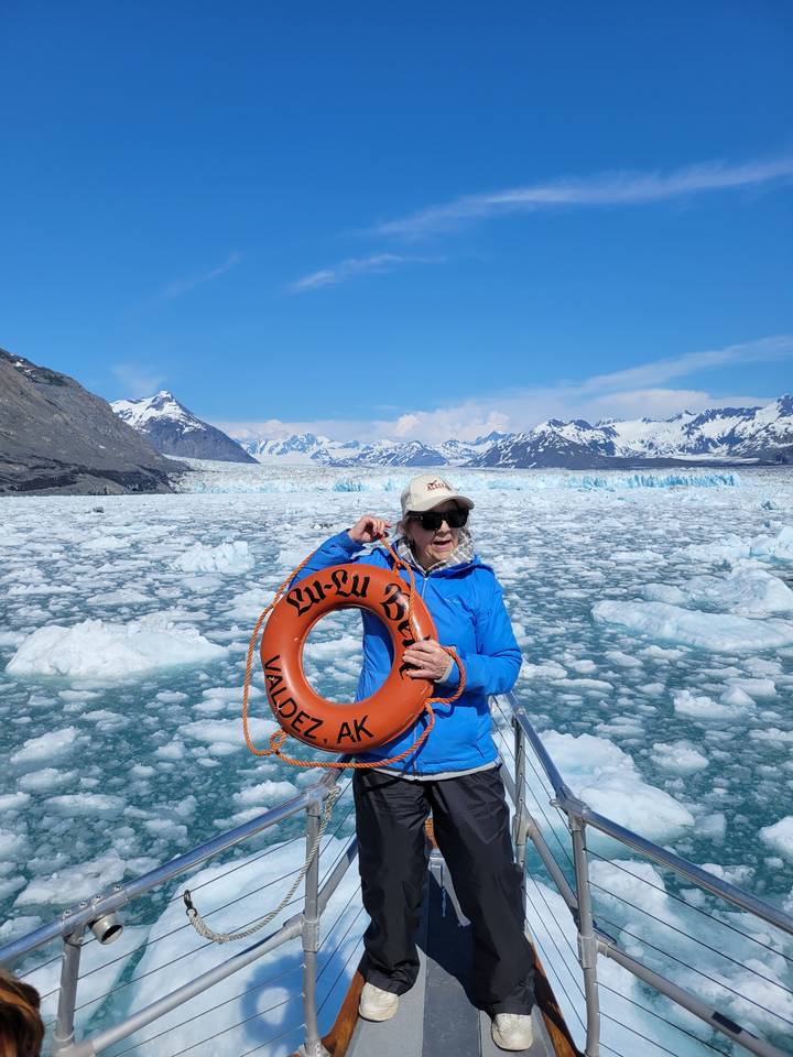 Personne tenant une bouée de sauvetage sur un bateau entouré d'icebergs.