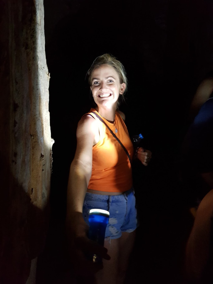 Femme souriant à l'intérieur d'une caverne faiblement éclairée.