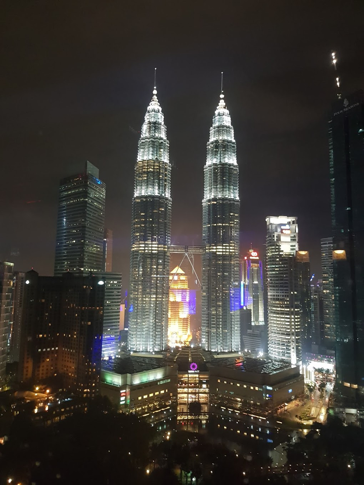 Les tours Petronas illuminées la nuit et le paysage urbain environnant.