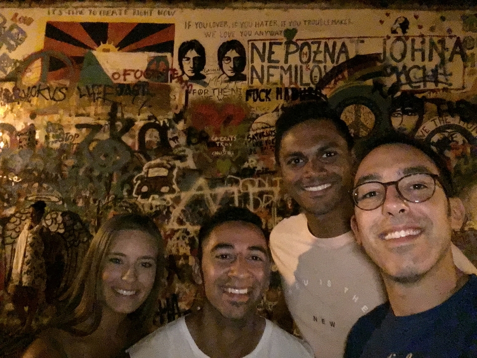 Groupe de personnes prenant un selfie contre un mur de graffitis la nuit.