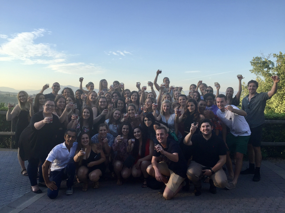 Grand groupe de personnes faisant la fête autour d'un verre au coucher du soleil.