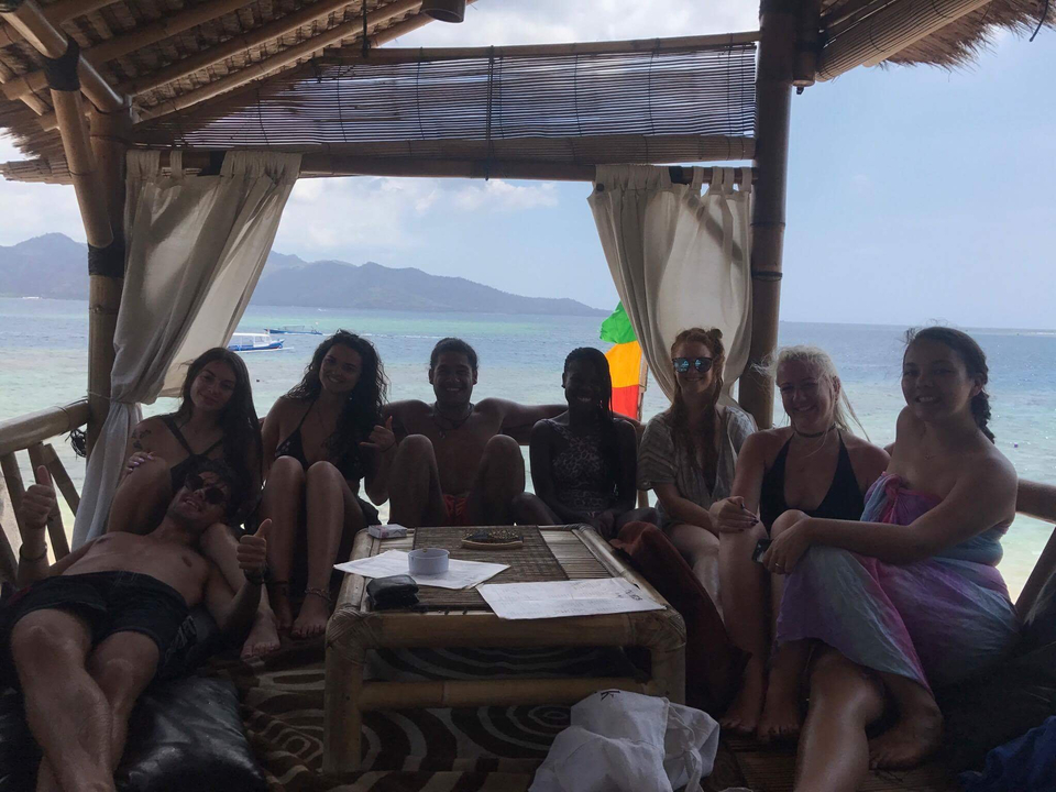 Group of people sitting in a beach hut with a scenic view.