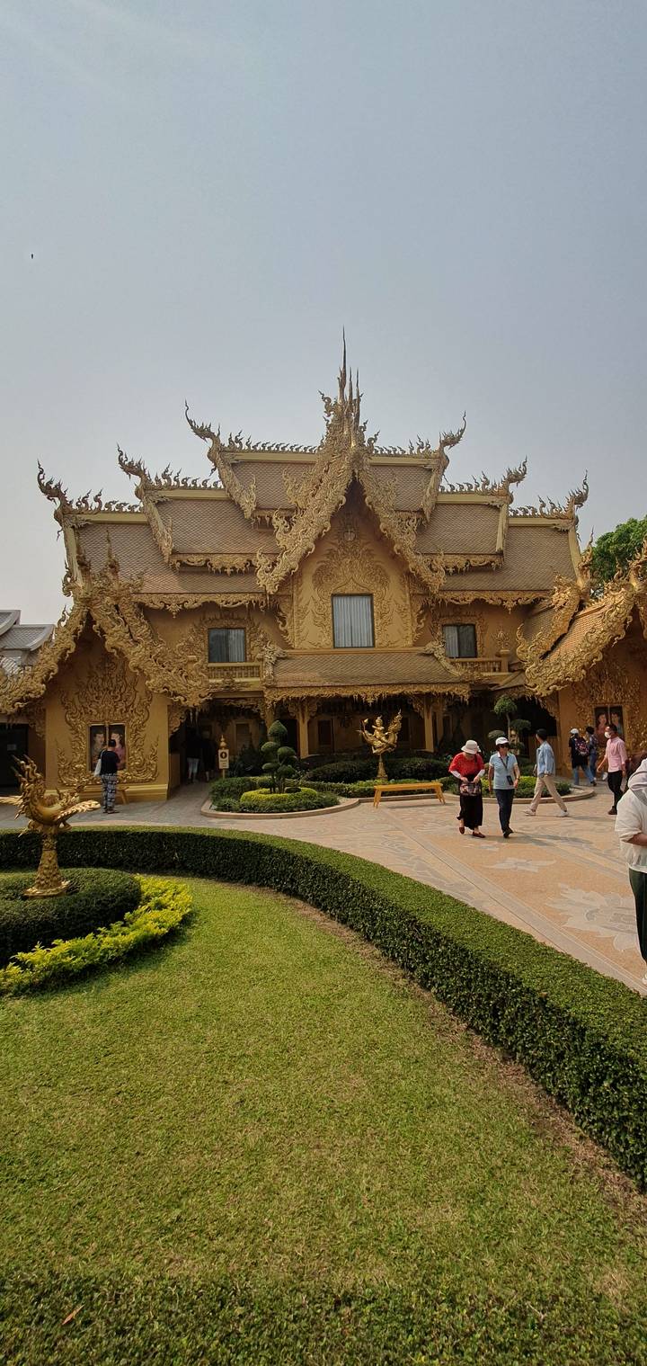Temple doré avec une architecture ornementée sculptée et des touristes.