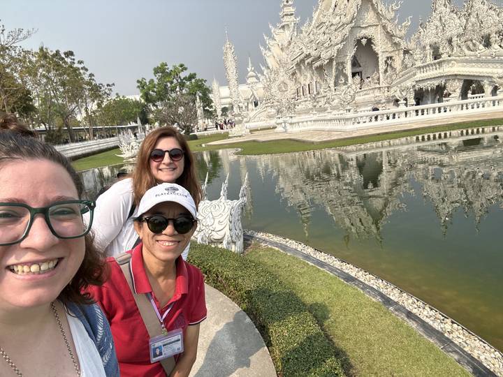 Des gens posant avec le reflet d'un temple.