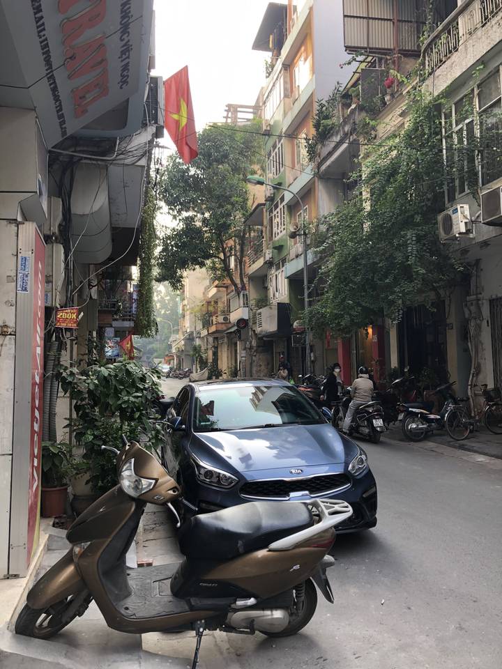 Vue de rue avec véhicules et drapeau vietnamien.